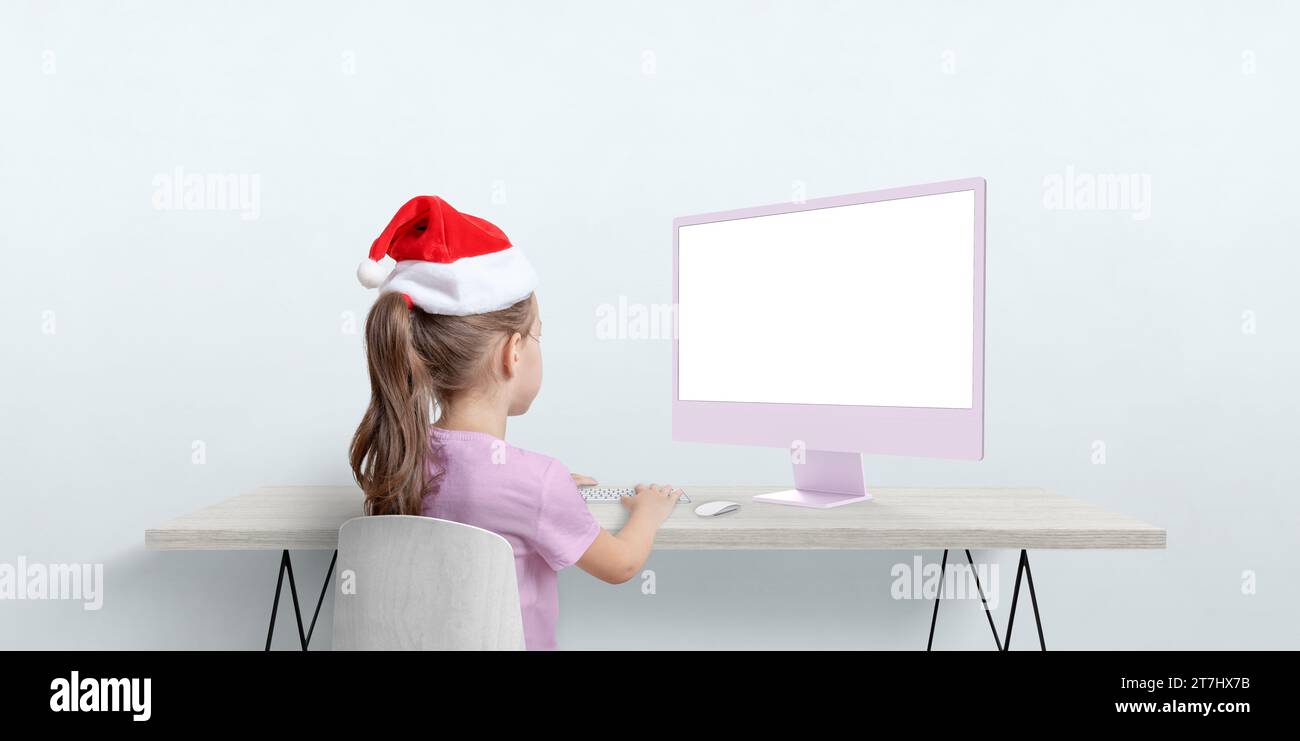 Weihnachtsmütze funktioniert auf Computermodellen an einem flachen Schreibtisch. Saisonale Fernarbeit mit Urlaubsgeist Stockfoto