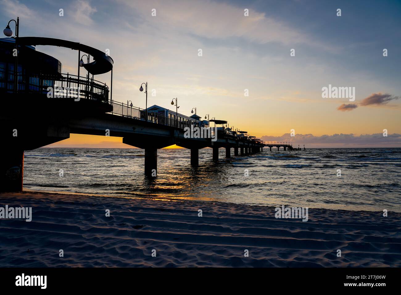 Pier am Strand in der Nähe von Misdroy in Polen. Natürlicher Küstenabschnitt an der polnischen Ostsee. Landschaft am Meer mit Sonnenuntergang am Pier. Stockfoto