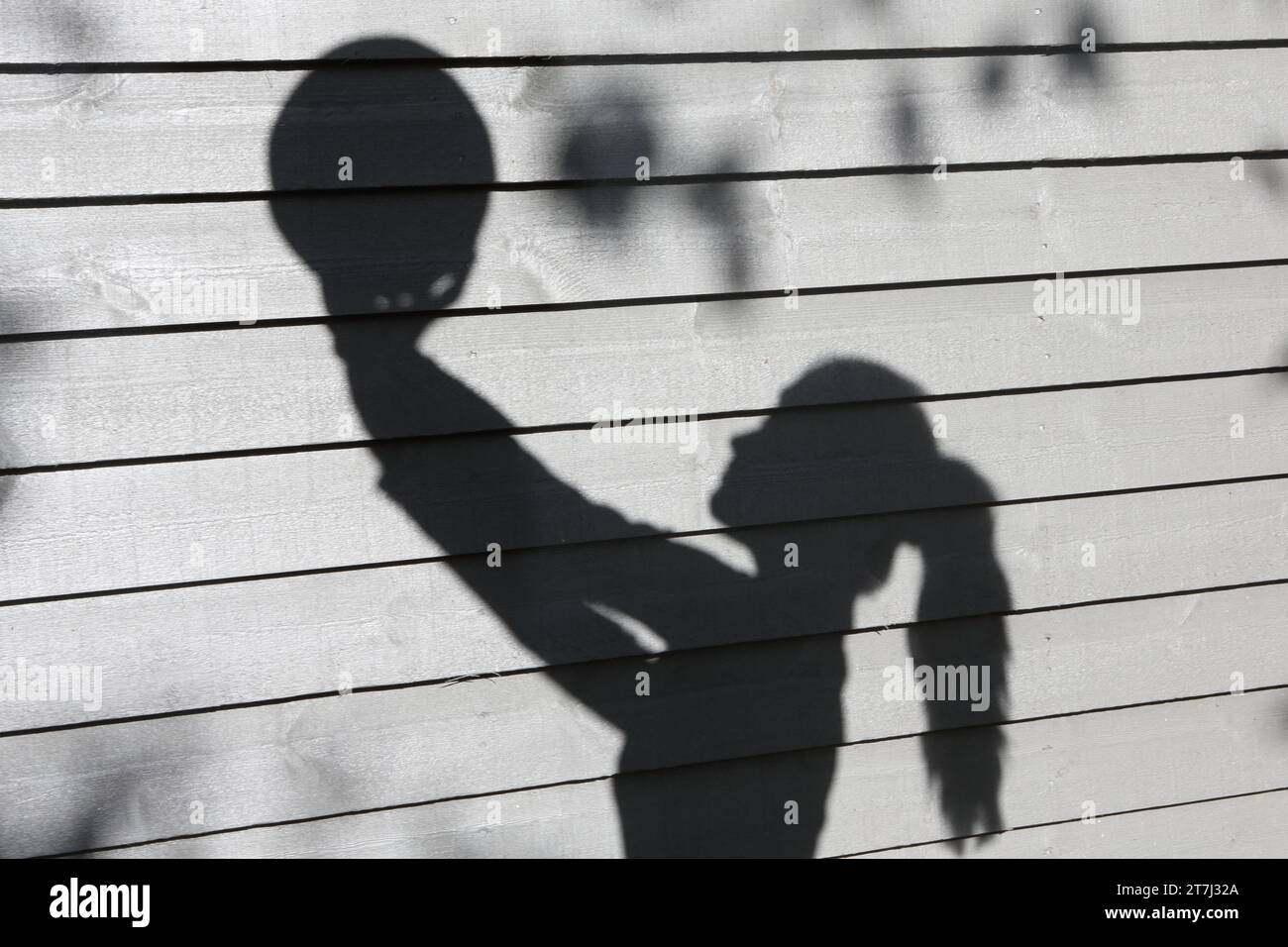 Schatten eines Teenagers, der Volleyball vor grauem Hintergrund hält Stockfoto