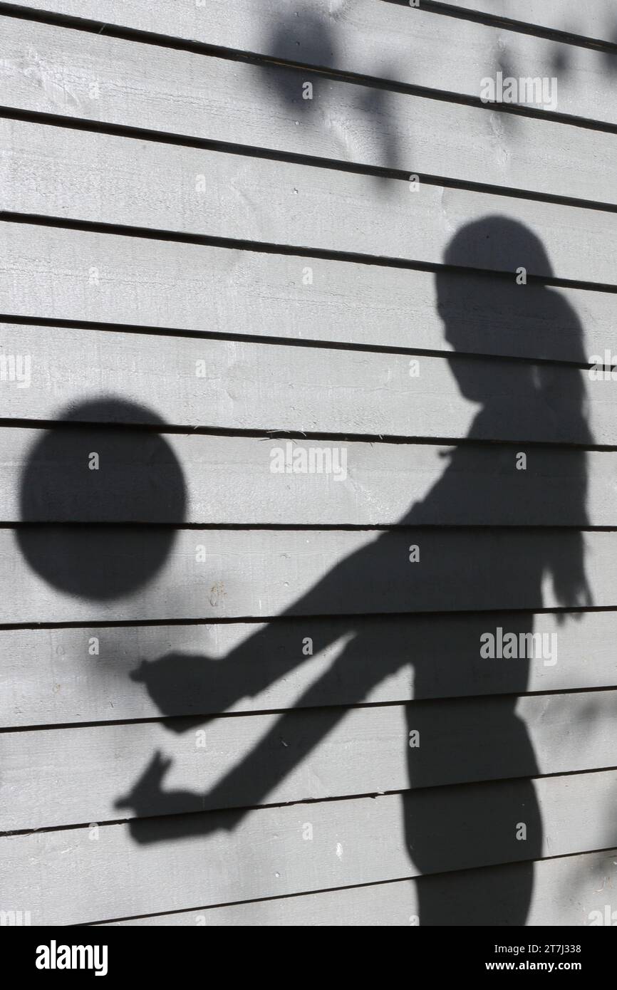 Teenager-Mädchen übt Volleyballschüsse - Schatten mit Ball in der Luft und ausgestreckten Armen Stockfoto