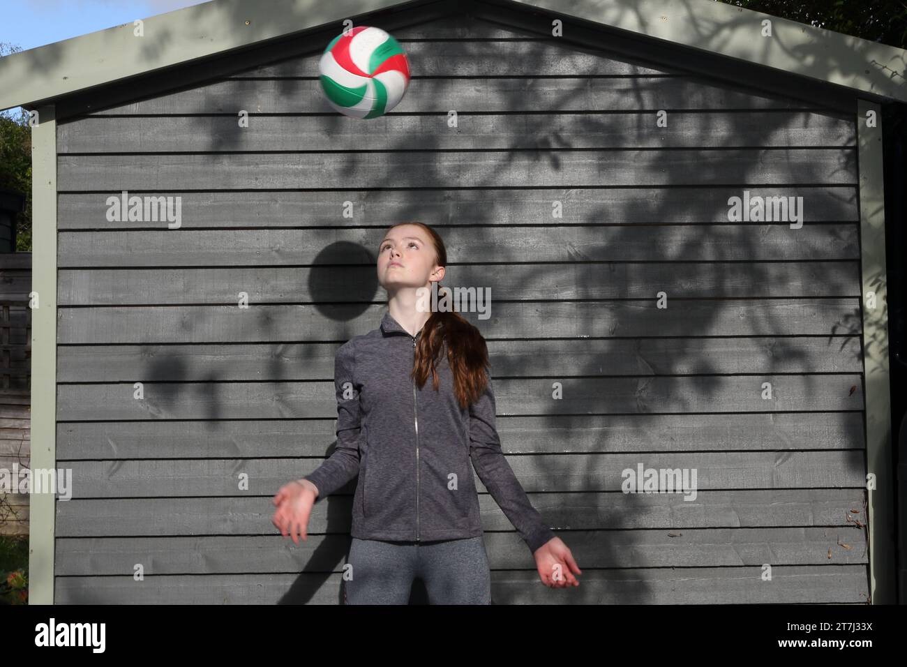 Das Teenager-Mädchen übt Volleyballschüsse und hält den Ball im Blick, wenn er höher schwimmt Stockfoto