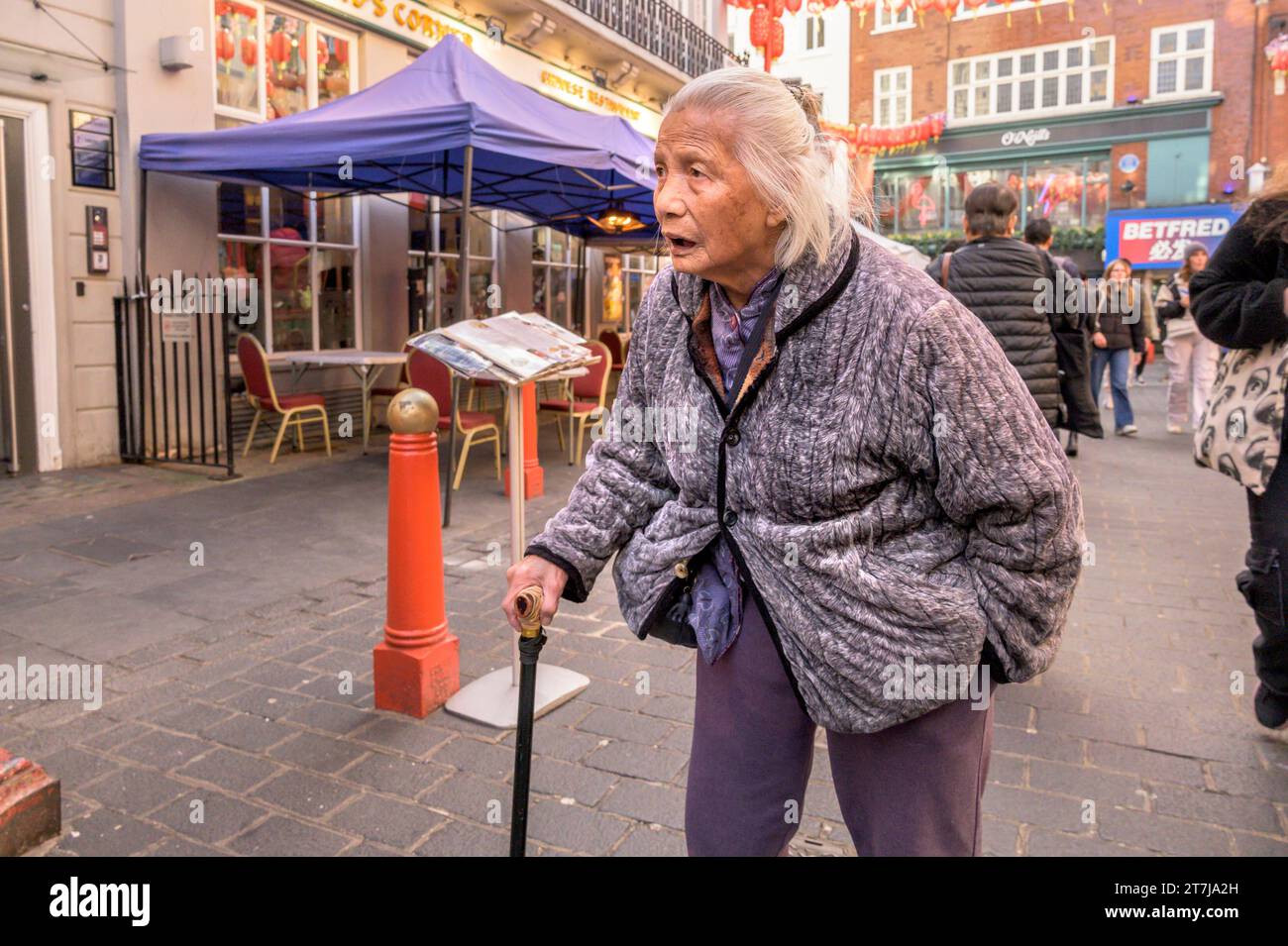 London, Großbritannien. Alte Frau mit einem Gehstock in der Gerrard Street, Chinatown Stockfoto