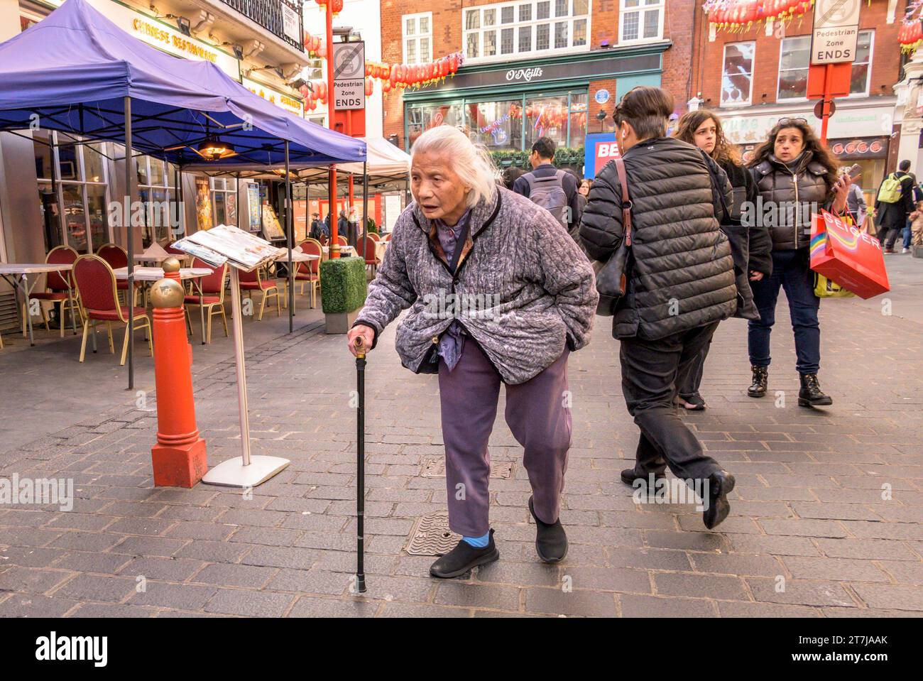 London, Großbritannien. Alte Frau mit einem Gehstock in der Gerrard Street, Chinatown Stockfoto