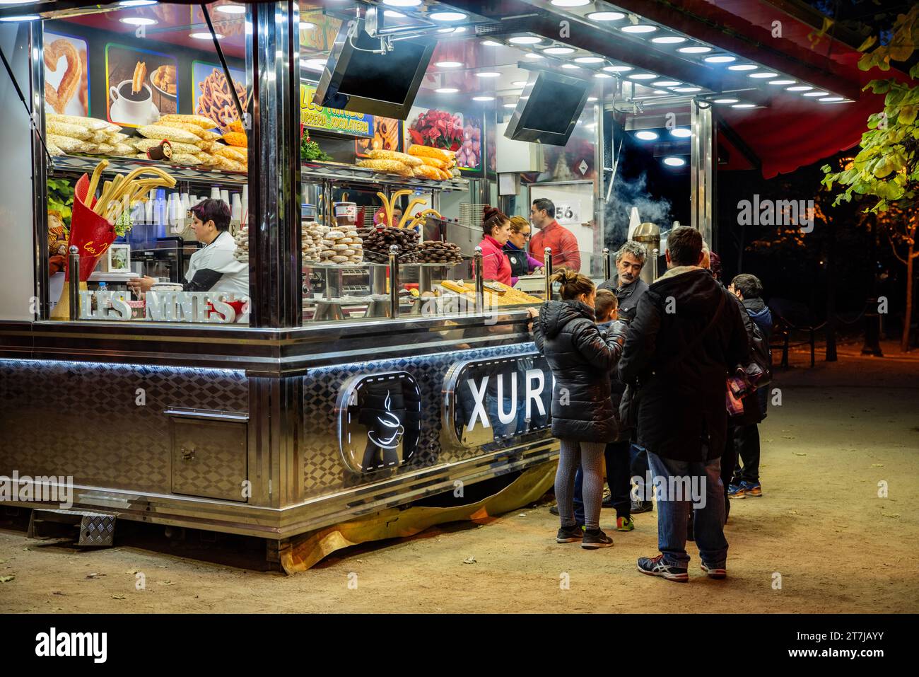 Erleben Sie die Essenz von Barcelonas Straßenleben: Ein traditioneller Churro-Stand strahlt Wärme, verführerische Aromen und lebhafte Treffen aus, während die Menschen sich verwöhnen Stockfoto