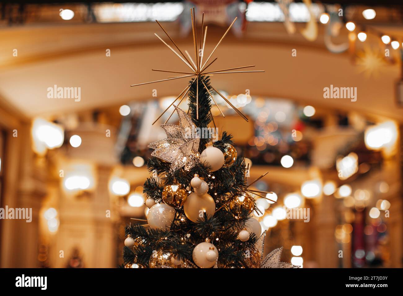 Zauberhafte, gemütliche Details, festliche Bokeh-Girlande im Hintergrund. Weihnachtsbaum mit Weihnachtskugeln, Kristallblume und goldener Girlande. Stockfoto