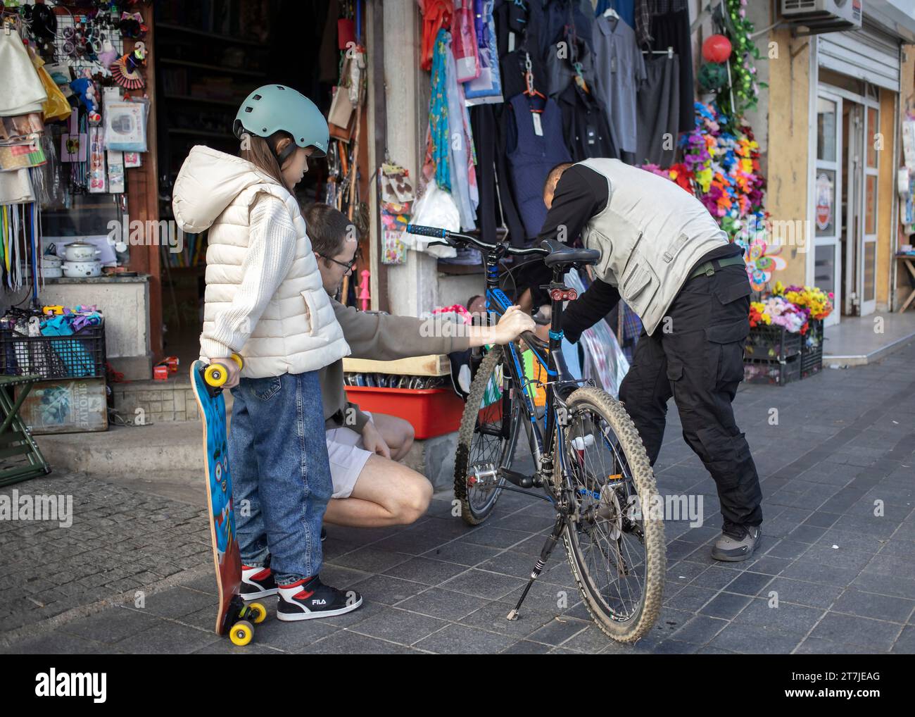 Belgrad, Serbien, 7. November 2023: Ein Verkäufer aus einem lokalen Geschäft hilft einem Mann mit einer Tochter, ein Fahrrad zu reparieren Stockfoto