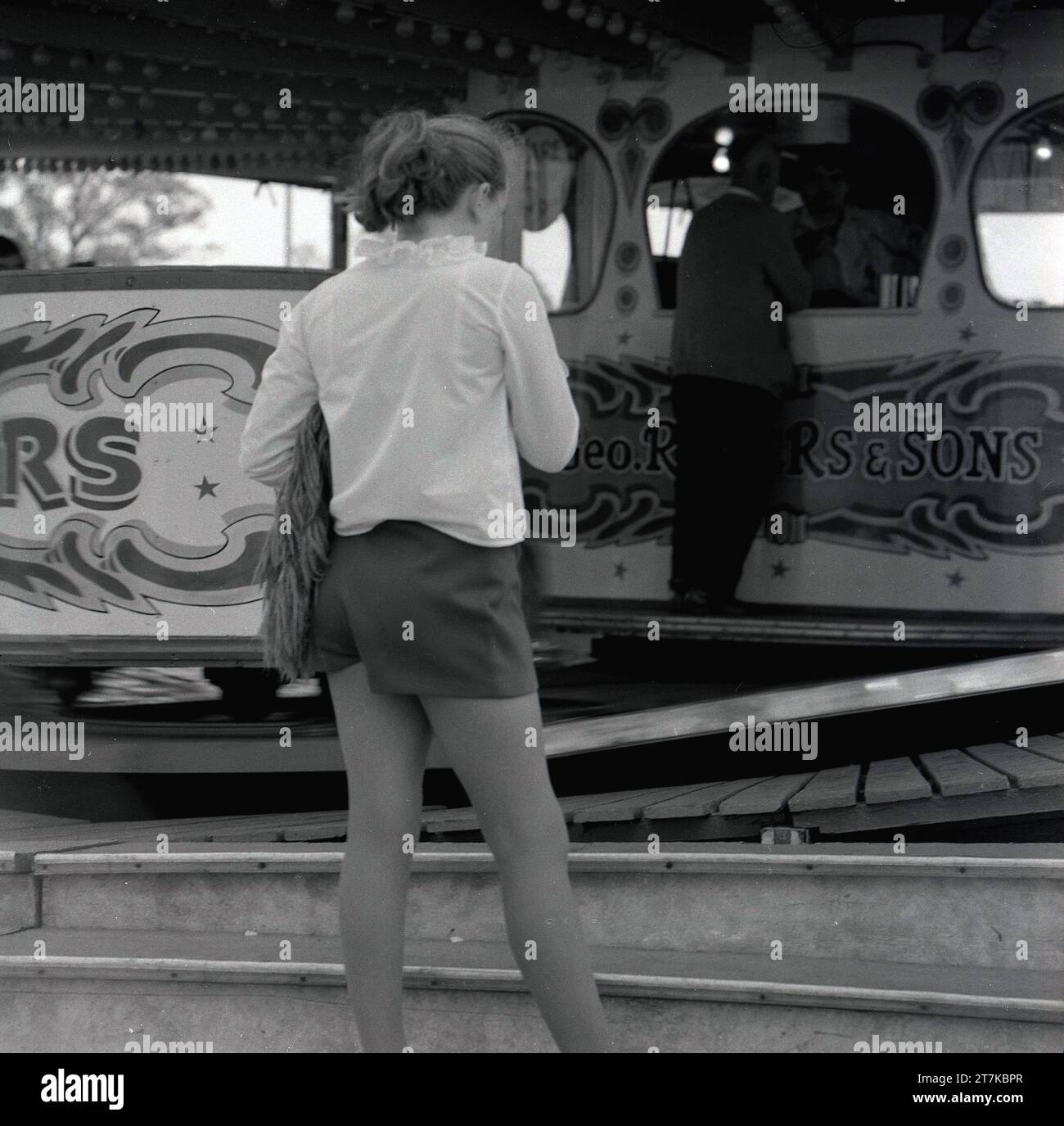 1970er Jahre, Teeenage Mädchen in Shorts und Bluse, stehend bei einer Fahrt auf einem Messegelände, England, Großbritannien. Stockfoto