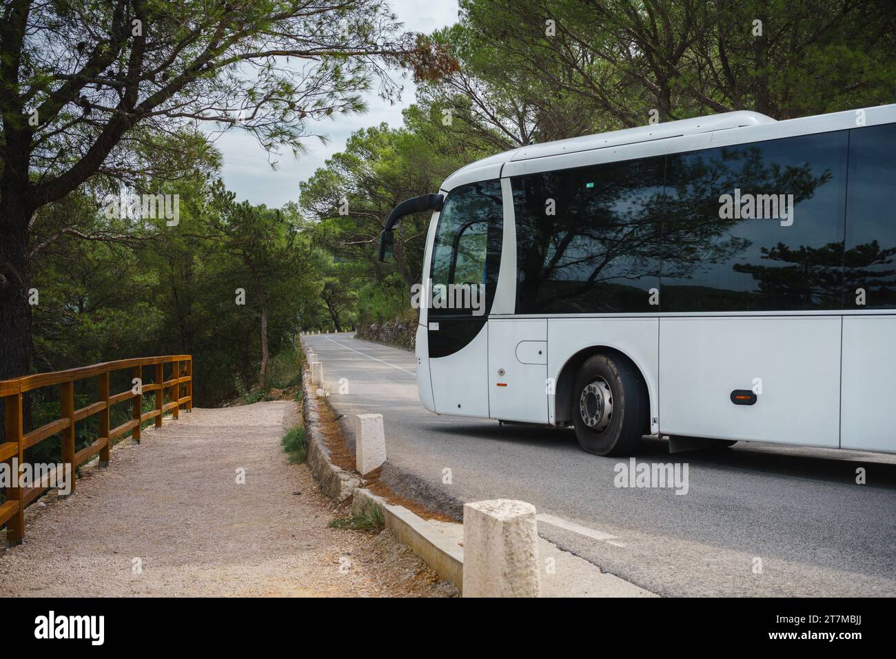 Weißer Touristenbus, der um eine enge Ecke in einer Bergstraße fährt Stockfoto