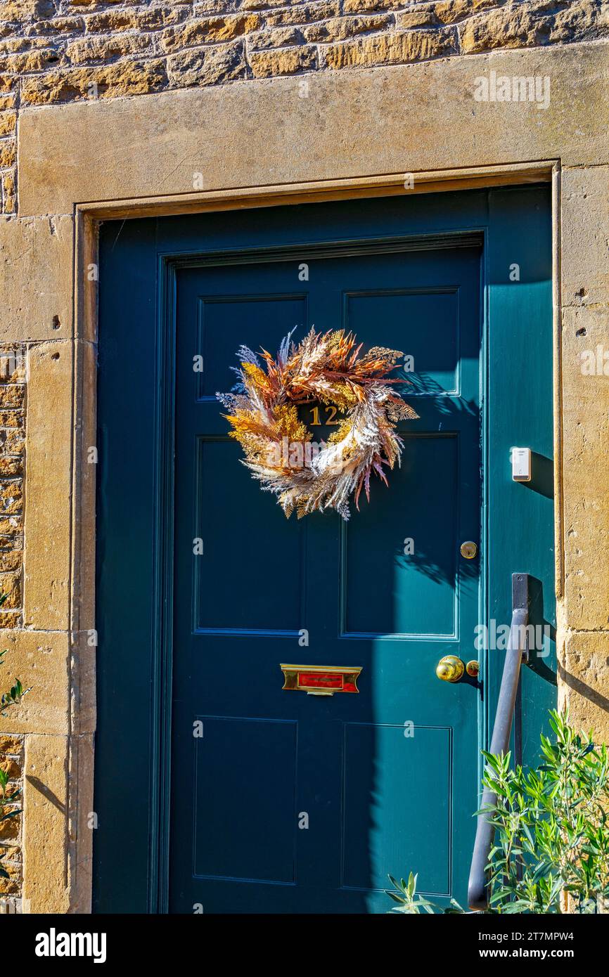 Ein attraktiver und künstlerischer Kranz in herbstlichen Farben an einer Tür in der East Street in Lacock Village, Wiltshire, England, Großbritannien Stockfoto
