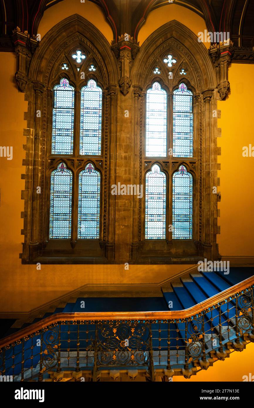 Treppe der Glasgow University mit blauem Teppich und kunstvollen Holzfenstern, Glasgow, Schottland, Großbritannien Stockfoto