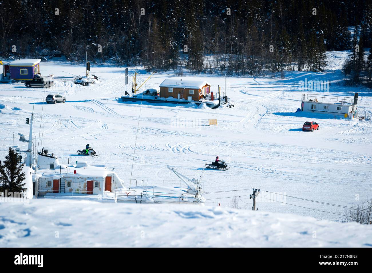 Überblick über den gefrorenen Slave Lake mit auf dem Eis gefrorenen Hausbooten, wo die Einheimischen das ganze Jahr über leben und im Winter mit dem Schneemobil oder Auto ihre Häuser erreichen. Stockfoto