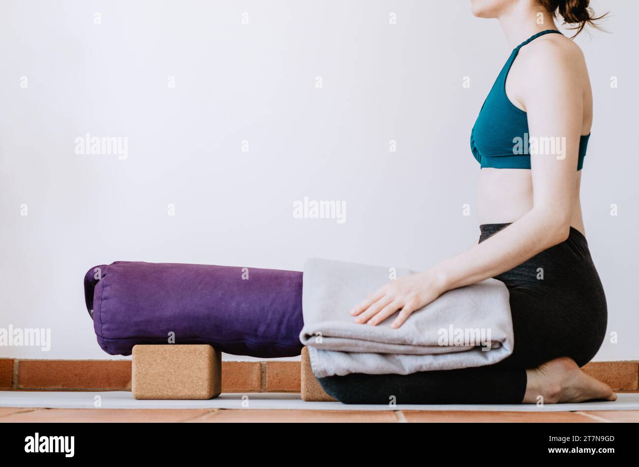 Frau, die sich auf eine restaurierende Yoga-Kinderhaltung mit Requisiten vorbereitet Stockfoto