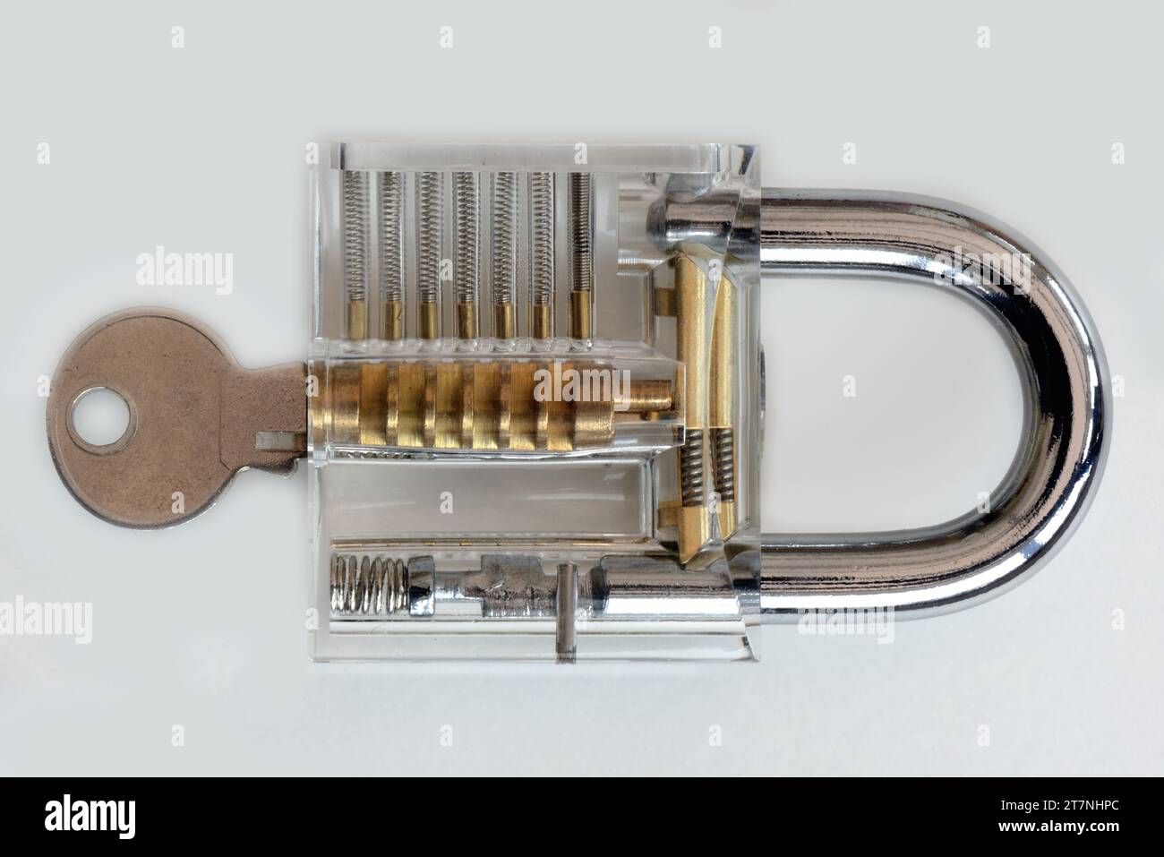 Ein durchsichtiges Vorhängeschloss aus transparentem Kunststoff mit Schlüssel auf neutralem Hintergrund, das das Konzept der Sicherheit angibt. Stockfoto