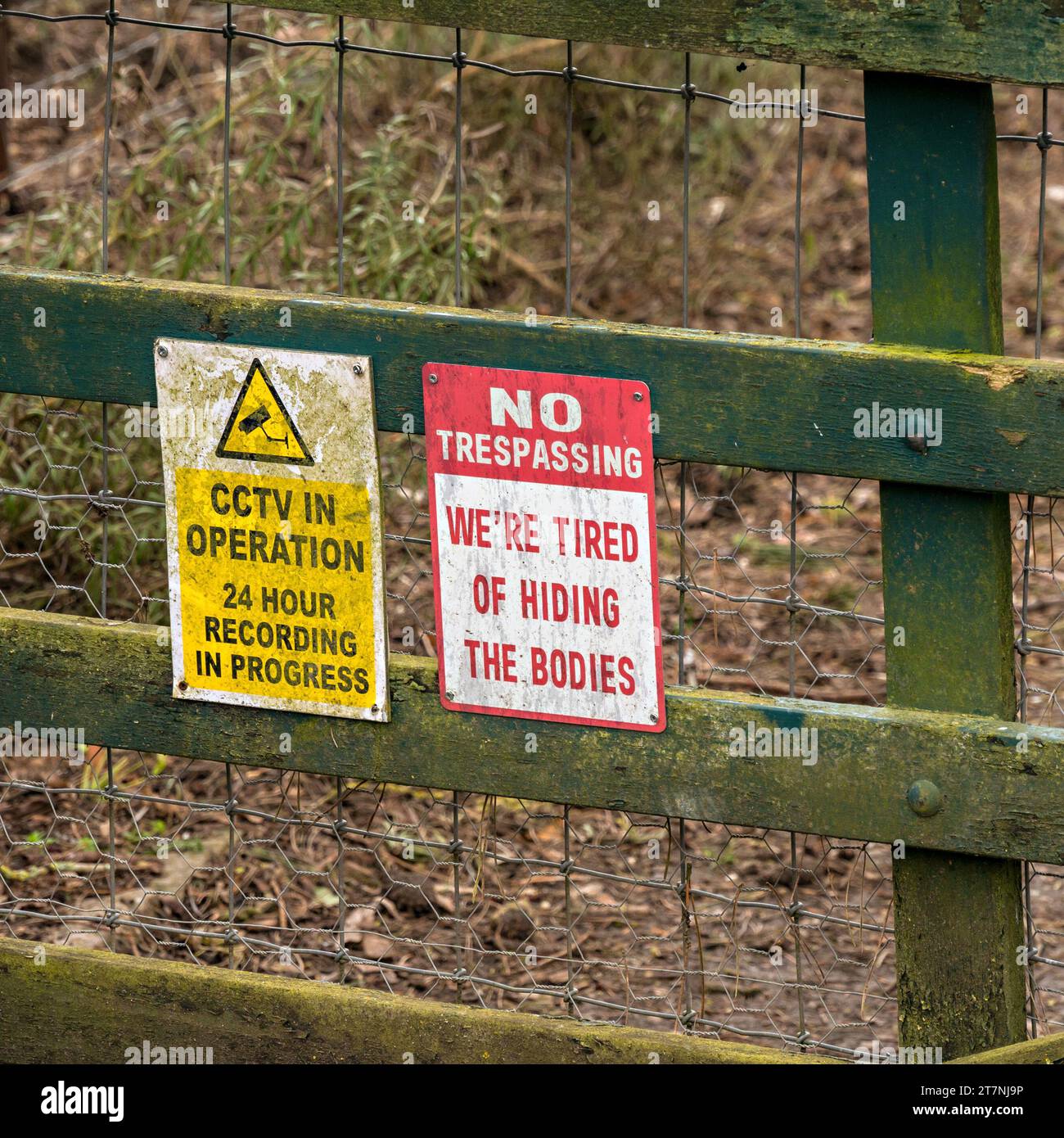 Warnung CCTV in Betrieb und humorvoll kein Betreten von Schildern auf Holzzaun, England, Großbritannien Stockfoto