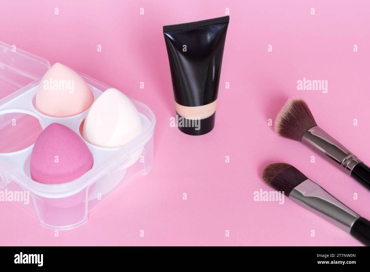 Make-up Foundation, Make-up Schwamm und Pinsel auf rosa Hintergrund. Kosmetisches Werkzeugkonzept. Kosmetikaccessoires. Stockfoto