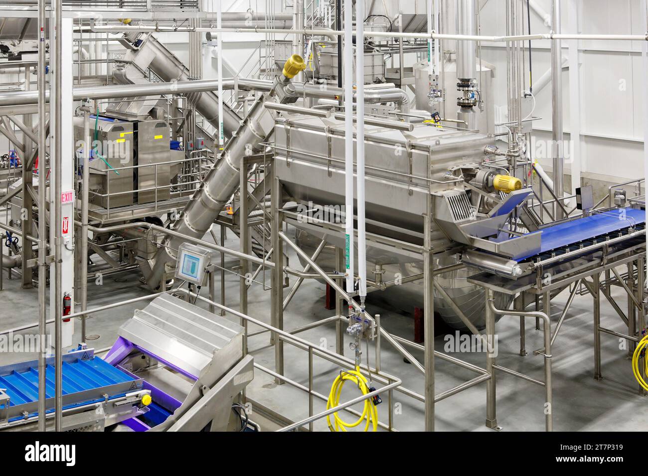 Maschinen, Schnecken, Öfen und Förderbänder aus rostfreiem Stahl, die zur Dehydrierung und Zubereitung von Lebensmitteln in einer sauberen, modernen Lebensmittelverarbeitungsanlage verwendet werden. Stockfoto