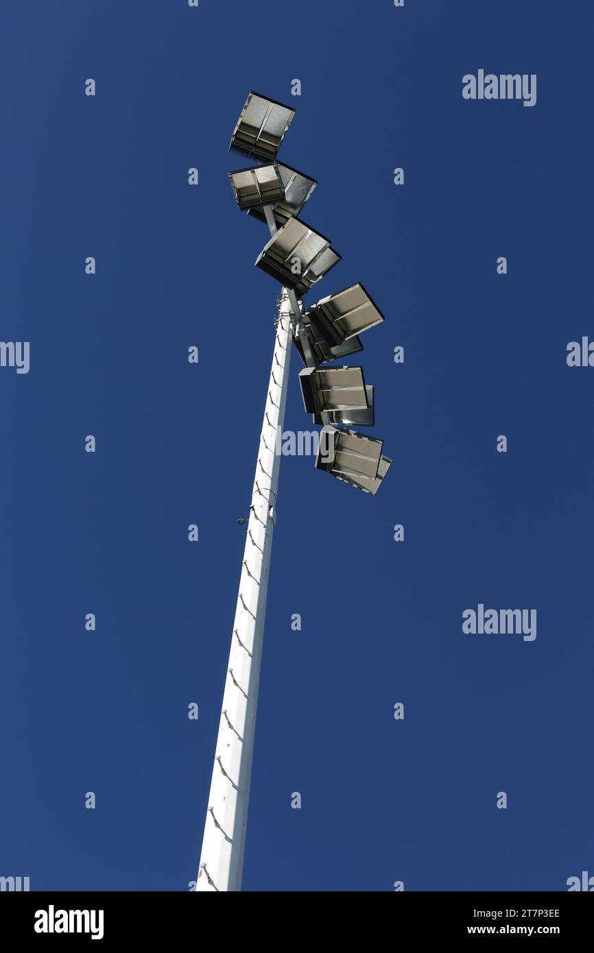 Neue, moderne, energiesparende Stadionlichter, isoliert vor einem blauen Himmel und hoch oben auf Stangen montiert, um ein Highschool-Fußballstadion zu beleuchten Stockfoto