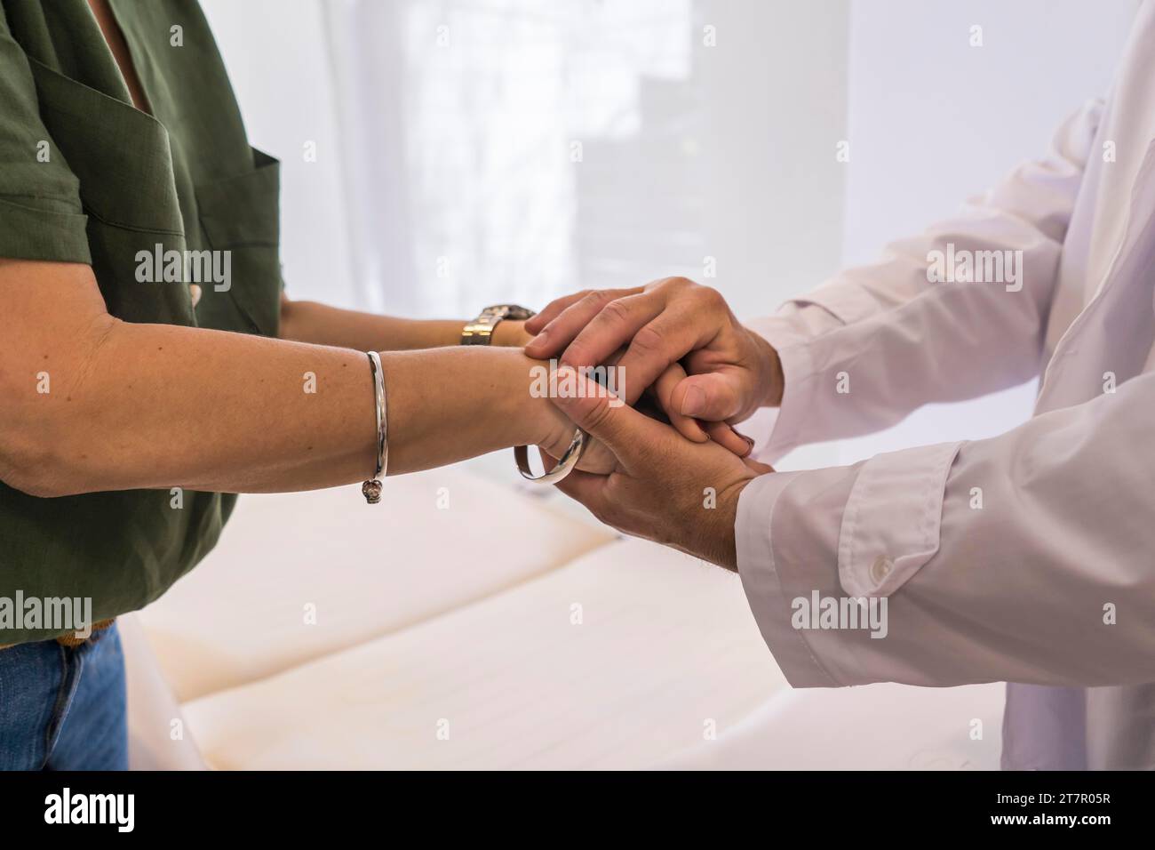 Männlicher Arzt hält Hände mit seiner Patientin im Krankenhaus Stockfoto