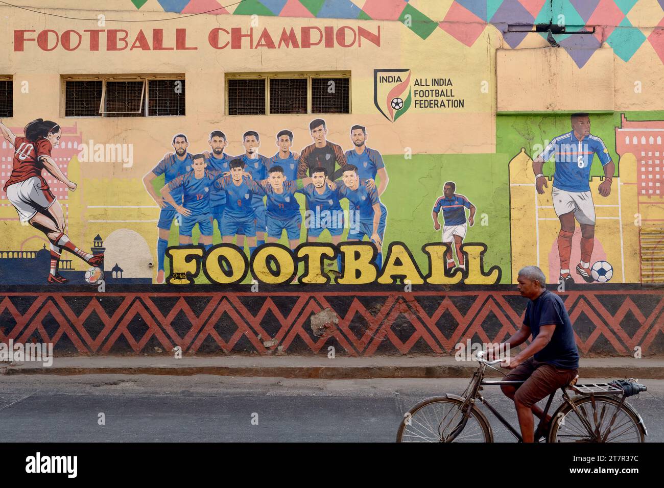 Ein Radfahrer in Byculla, Mumbai, Indien, passiert ein großes Wandgemälde des All India Football Federation, das den Fußballweltmeister Argentinien 2022 feiert Stockfoto