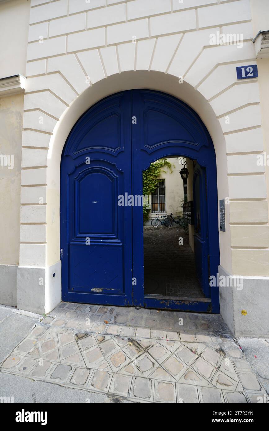 Eine geöffnete blaue Tür eines alten Gebäudes im 4. Arrondissement in Paris, Frankreich. Stockfoto