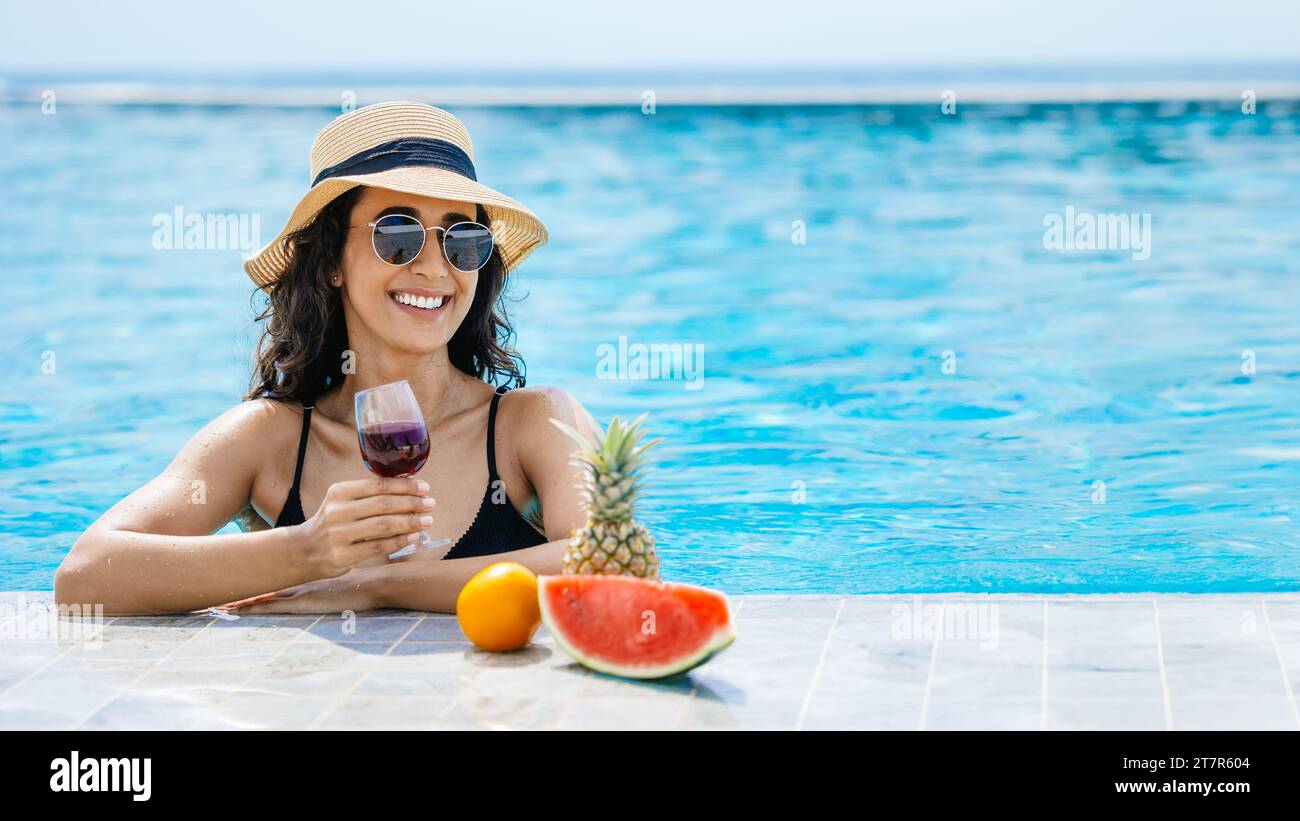 Glückliche lächelnde Bikinifrau Genießen Sie Entspannung am Swimmingpool mit tropischen Früchten Drinks Wein Sommer Ruheurlaub. Touristen-Mädchen genießen Urlaub chillen Stockfoto