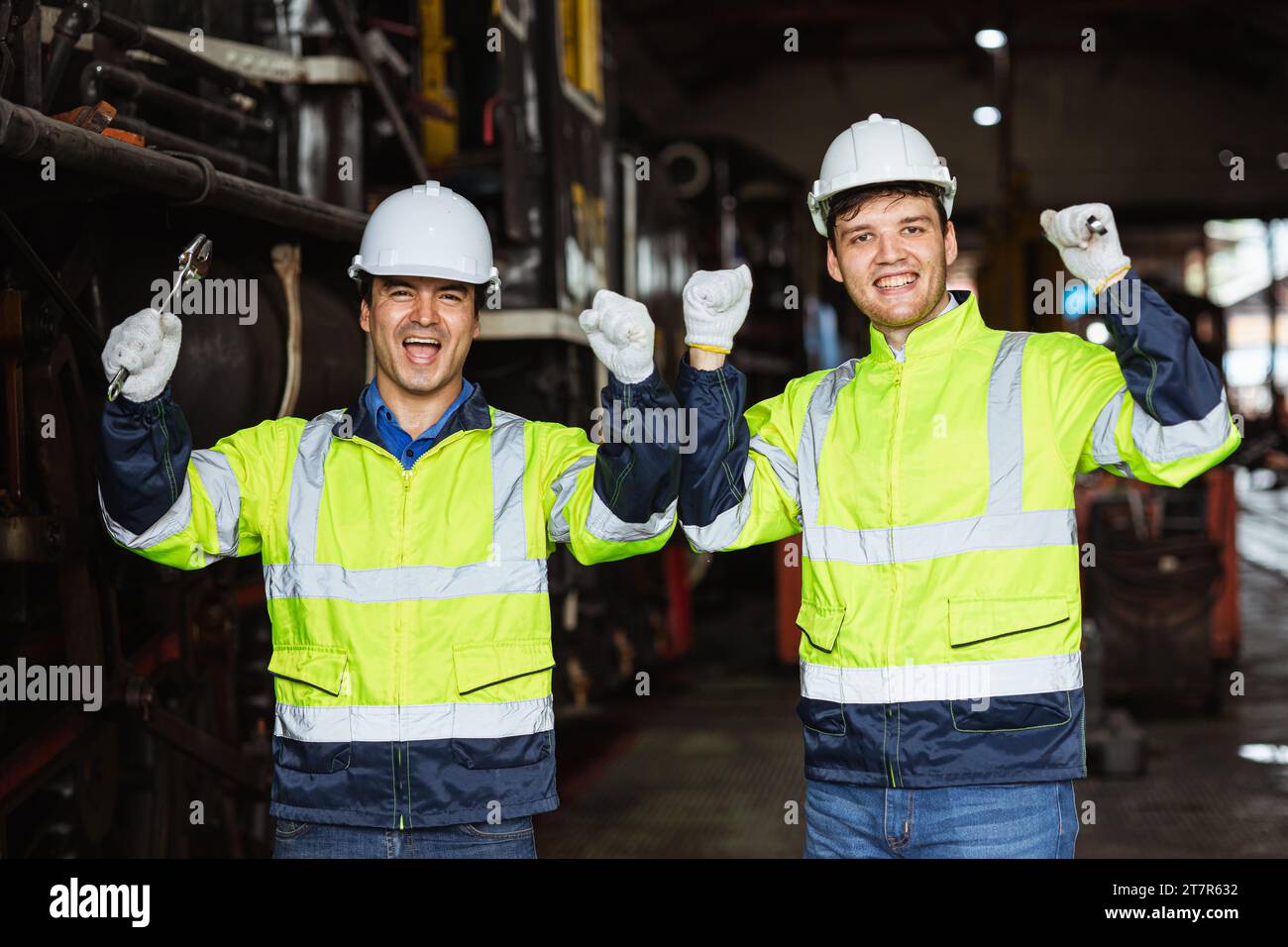 Glücklicher, fröhlicher Ingenieur männlicher Teammechaniker Mitarbeiter, der reflektierende Sicherheitskleidung mit Schutzhelm trägt, genießt das Lächeln zusammen Stockfoto
