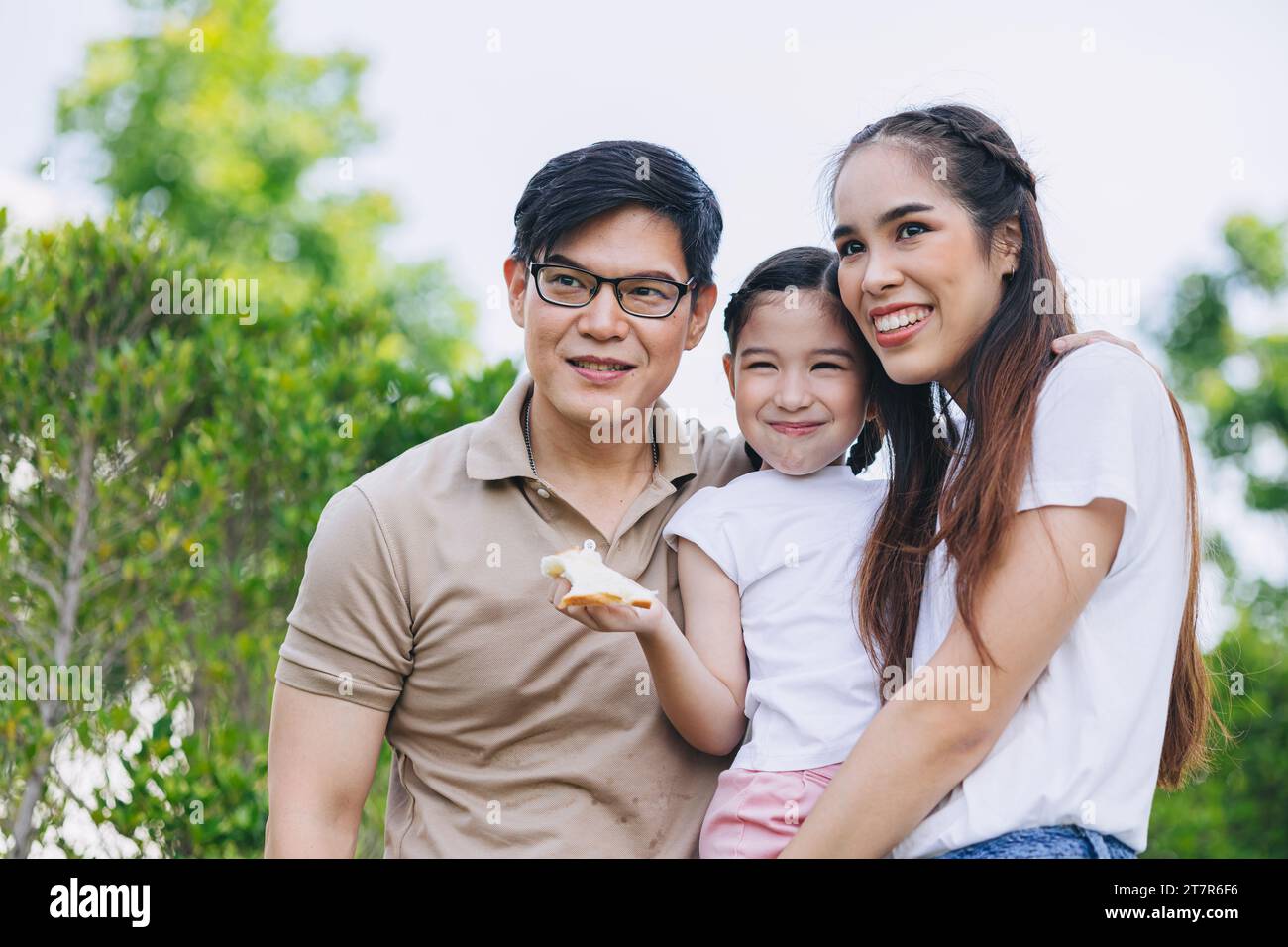 Glücklich lächelnde junge asiatische Familie Glück mit Kind, kleines Mädchen, das zusammen im grünen Park steht Stockfoto