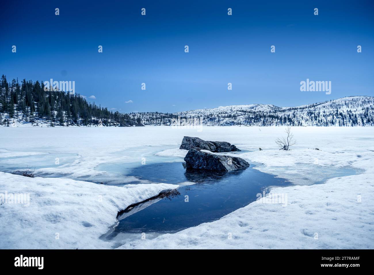 Gefrorener See mit schneebedeckten Bergen nach tiefem Schneefall im Winter Stockfoto