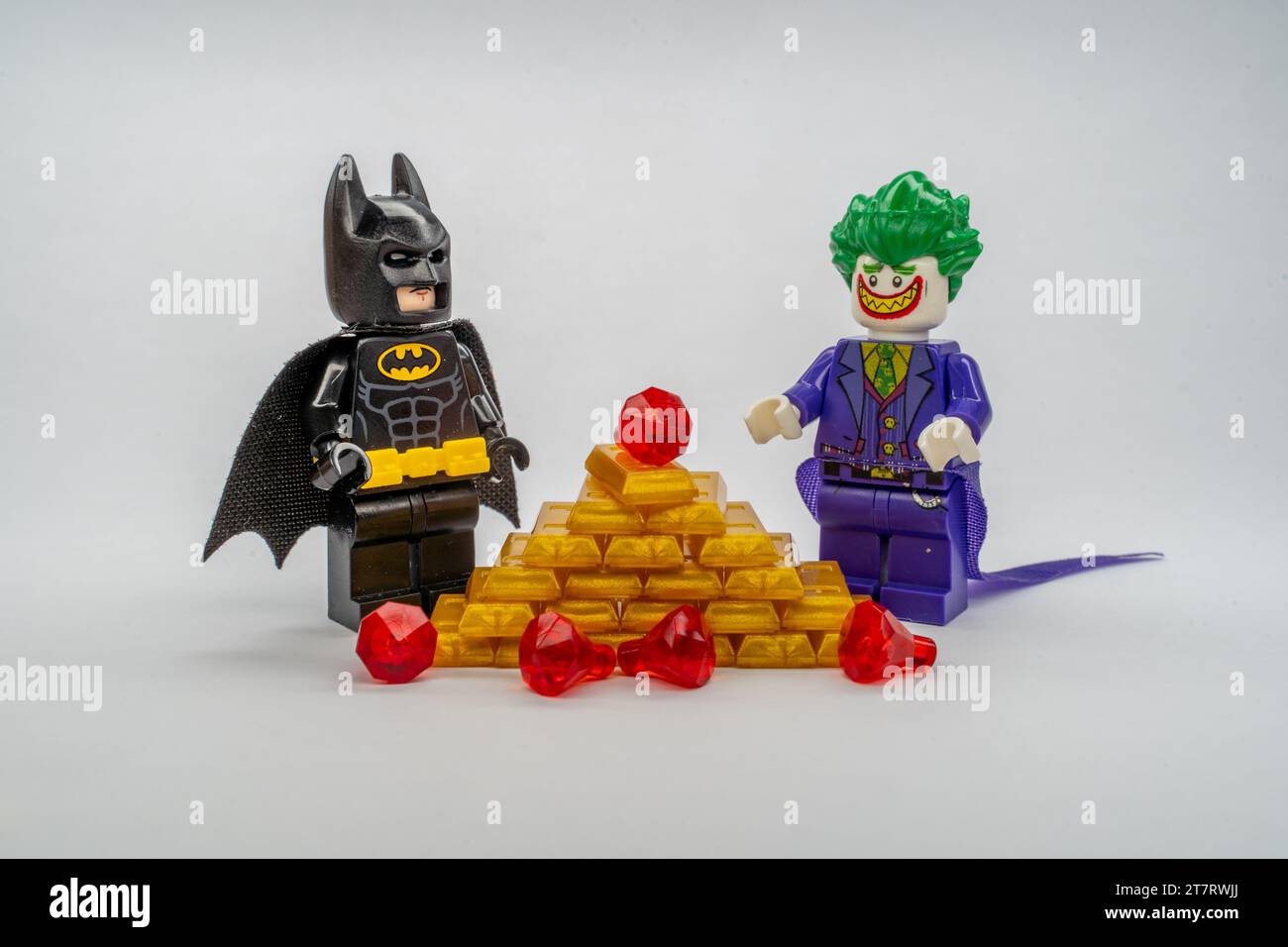 Die LEGO Figuren von Batman und Joker stehen vor einem Stapel goldener LEGO-Stücke. Stockfoto