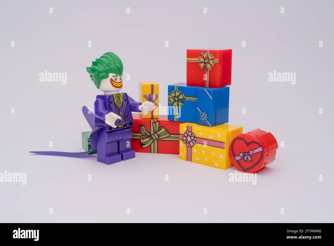 Eine Lego-Figur von Joker neben einem Stapel bunter Geschenkboxen. Stockfoto