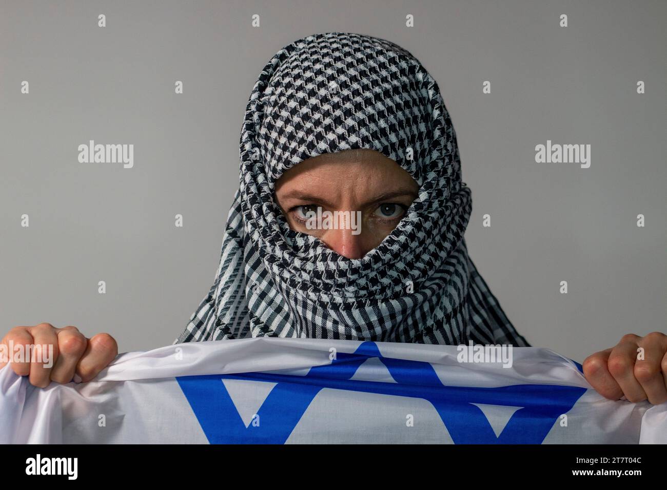 Grünäugige Frau mit palästinensischem Kopftuch und israelischer Flagge. Konfliktkonzept Stockfoto