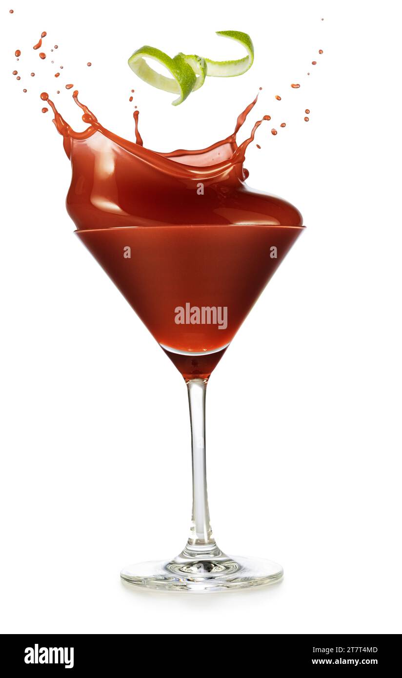 Spiralförmige Limettenschale, die in einen spritzenden roten Cocktail fällt, serviert in klassischem Martini-Becherglas isoliert auf weißem Hintergrund. Echte Studio-Foto-Aufnahme von ele Stockfoto