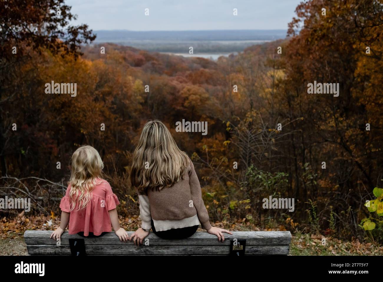 Zwei Personen sitzen auf der Bank und blicken auf das Herbstlaub Stockfoto