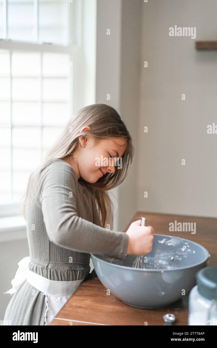 Lächelndes Mädchen, das Kekse in einer Schüssel mischt Stockfoto