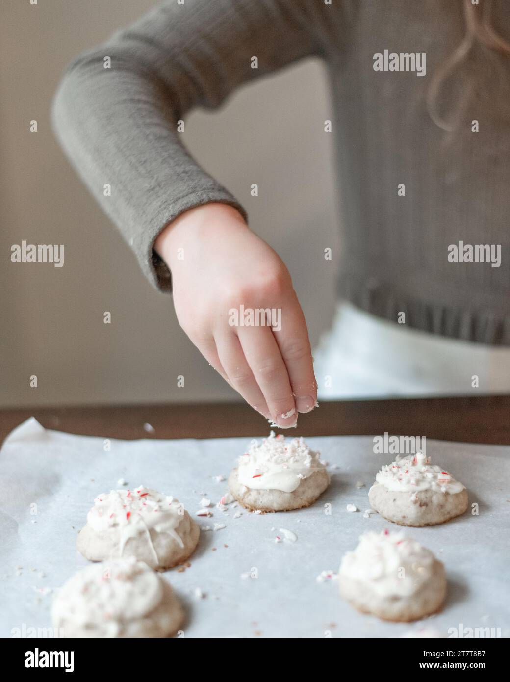 Ein Mädchen, das Zuckerrohr auf Kekse streut Stockfoto