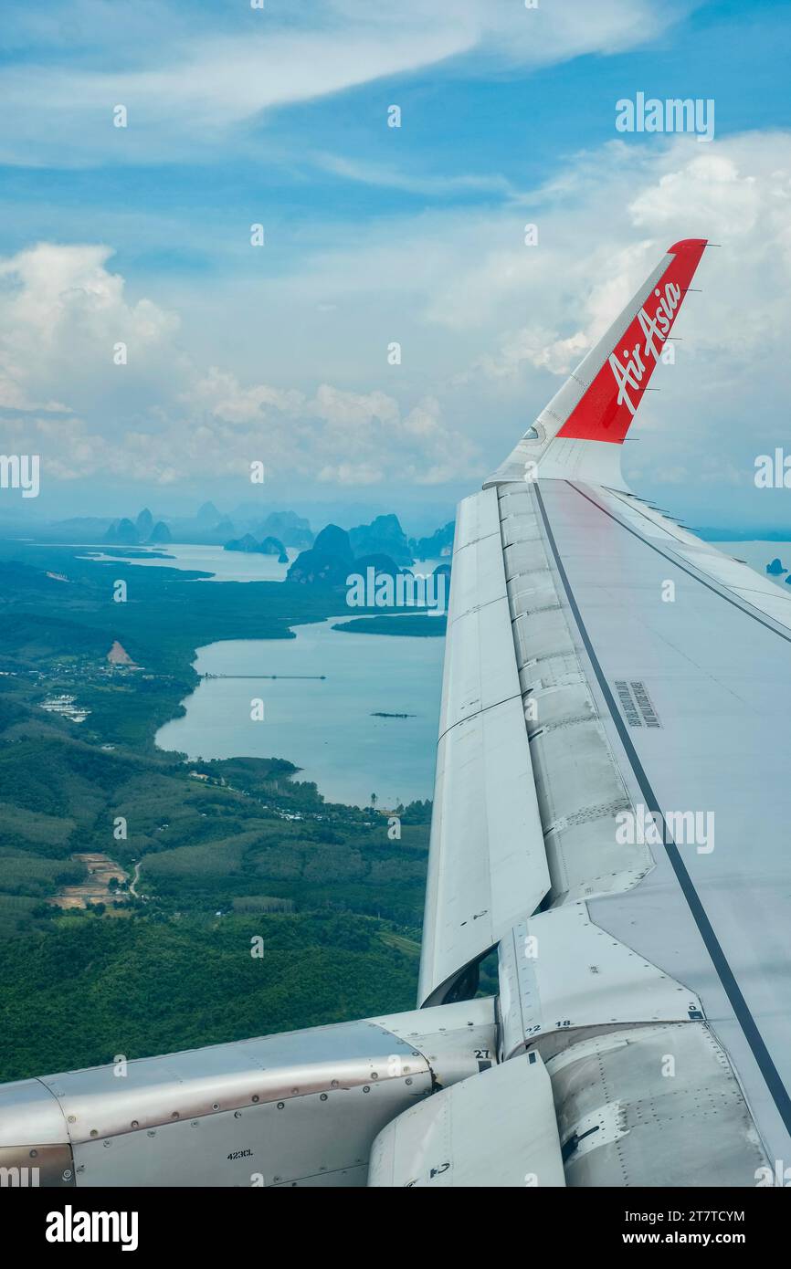 Flügel eines Air Asia Flugzeugs, das an einem sonnigen, aber trüben Tag über die Inseln der Andamanensee nach Phuket fliegt Stockfoto