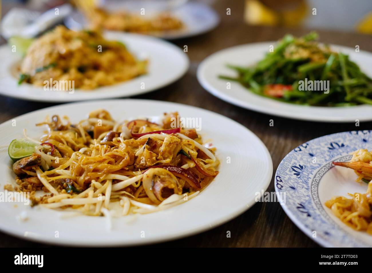 Ein vollständiger Tisch mit thailändischen Gerichten: Meeresfrüchte Pad thai, Huhn tom Yum gebratener Reis und gebratener Morgenruhm - in einem Strandrestaurant in Patong, Phuket Stockfoto