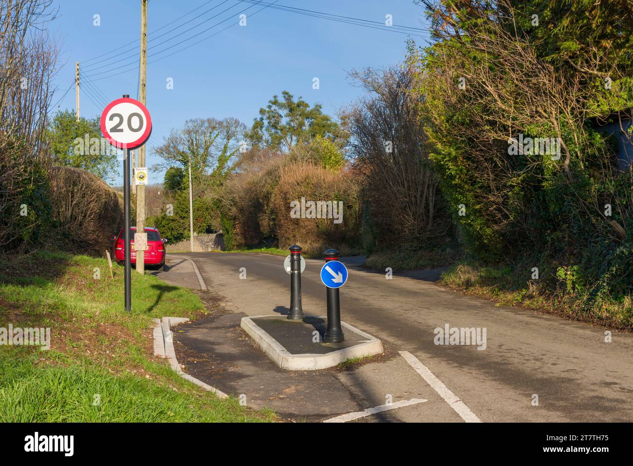 Ein Schild mit einer Geschwindigkeitsbegrenzung von 20 Meilen pro Stunde und Maßnahmen zur Verkehrsberuhigung auf einer Landstraße, wo es in das ländliche Dorf Wrington, North Somerset, England, eindringt. Stockfoto