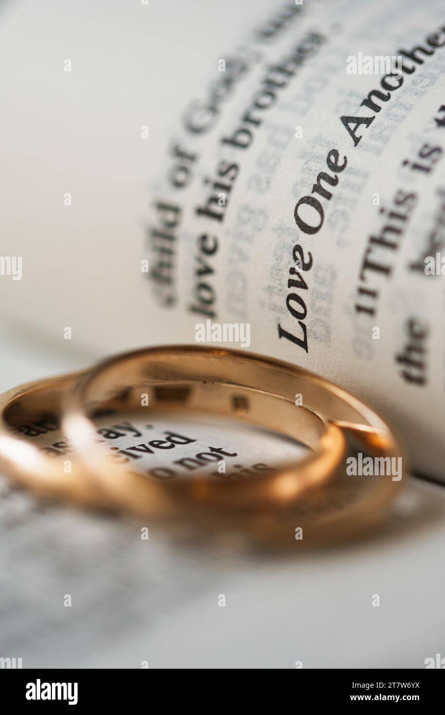 Zwei goldene Eheringe und geöffnete Seiten der heiligen Bibel repräsentieren das Konzept der Ehe und der Liebe zwischen zwei Christen Stockfoto