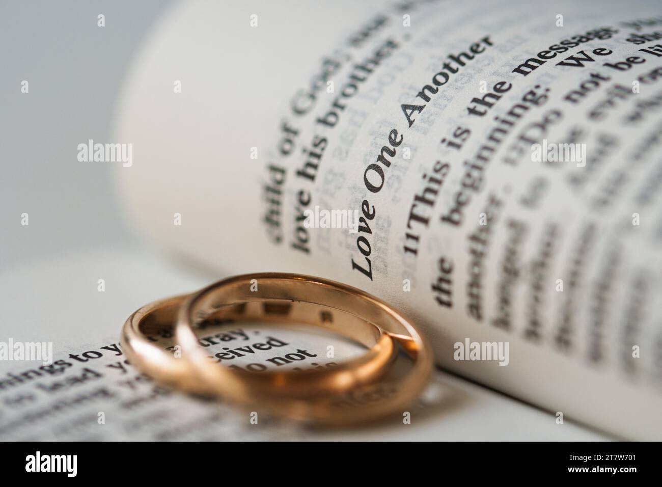 Zwei goldene Eheringe und geöffnete Seiten der heiligen Bibel repräsentieren das Konzept der Ehe und der Liebe zwischen zwei Christen Stockfoto