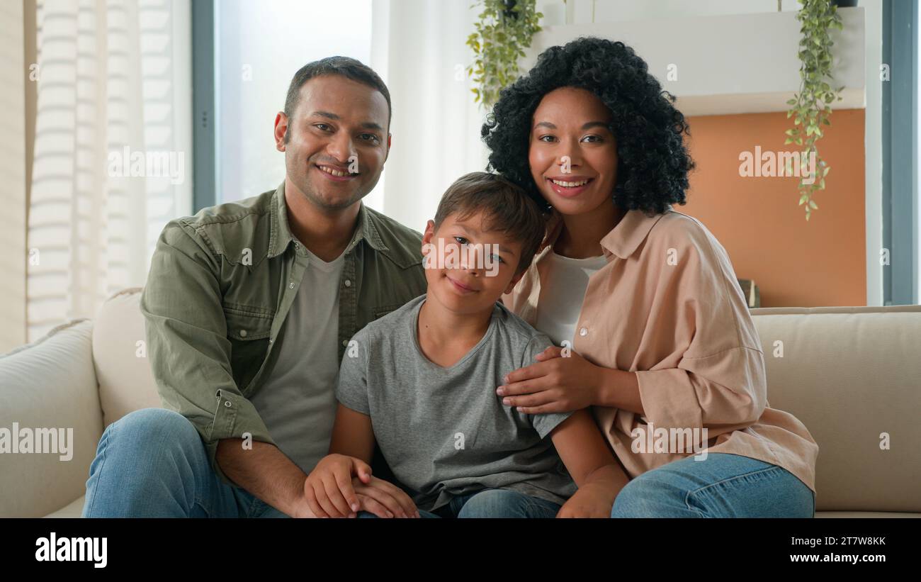Multirassisches afroamerikanisches Kaukasisches glückliches Familienporträt zu Hause lächelnde Eltern Vater und Mutter umarmen kleinen Jungen Kind im Vorschulalter auf Sofa Stockfoto