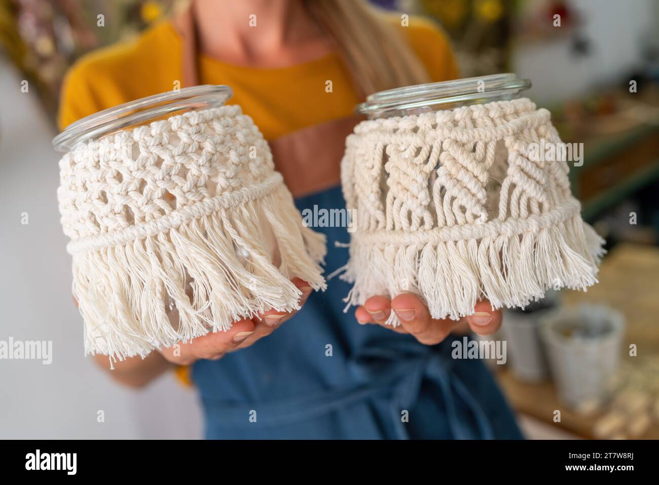 Nahaufnahme von Händen, die Makramee-verzierte Glasgläser halten Stockfoto