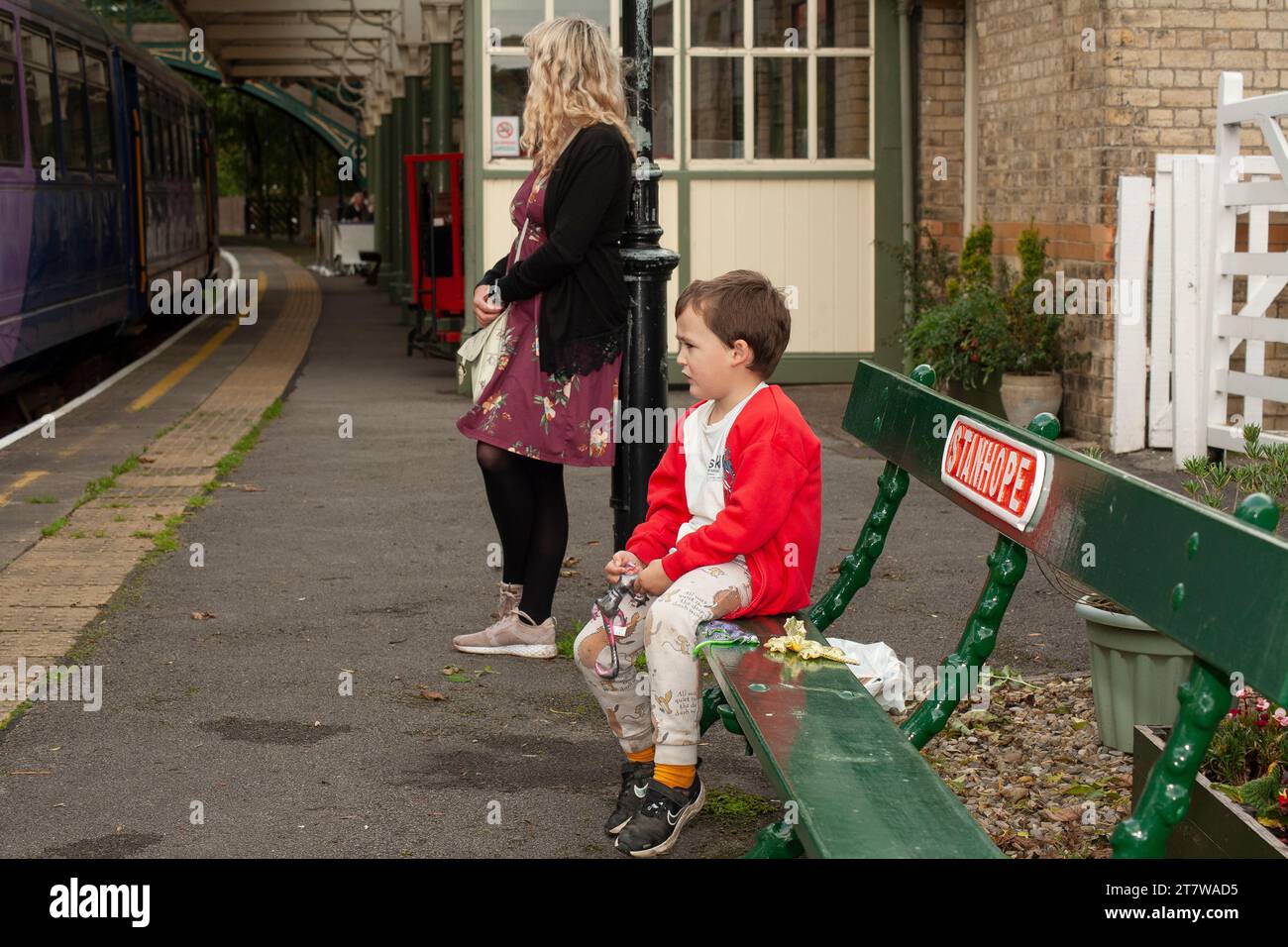 Ein 6-jähriger Junge und seine alleinerziehende Mutter warten geduldig auf die Ankunft des Zuges Stockfoto