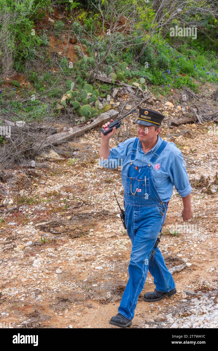 Eisenbahnangestellter, der sowohl als Zugbegleiter als auch als Bremser im Hill Country Flyer-Zug fungiert, verlässt das Heck des Zuges, um Schalter zu bedienen. Stockfoto