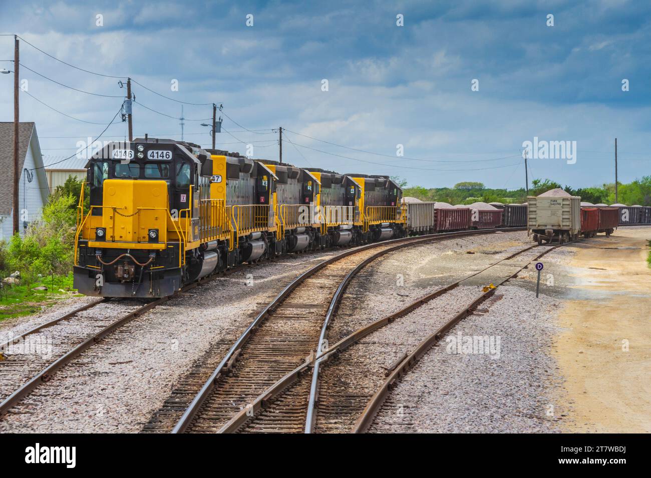 Moderne Zugmaschinen ziehen Güterzugwagen auf Seitenschienen, während die Fahrt mit dem Hill Country Flyer Tourist Train vorbeifährt. Stockfoto