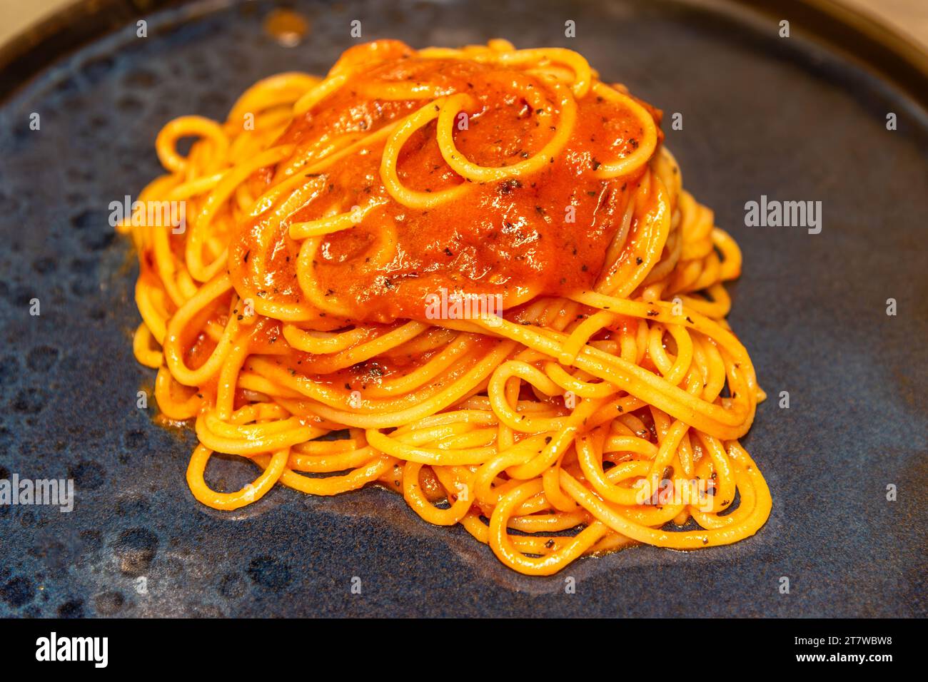 Spaghetti-Pasta mit Tomatensauce auf schwarzem Teller Stockfoto