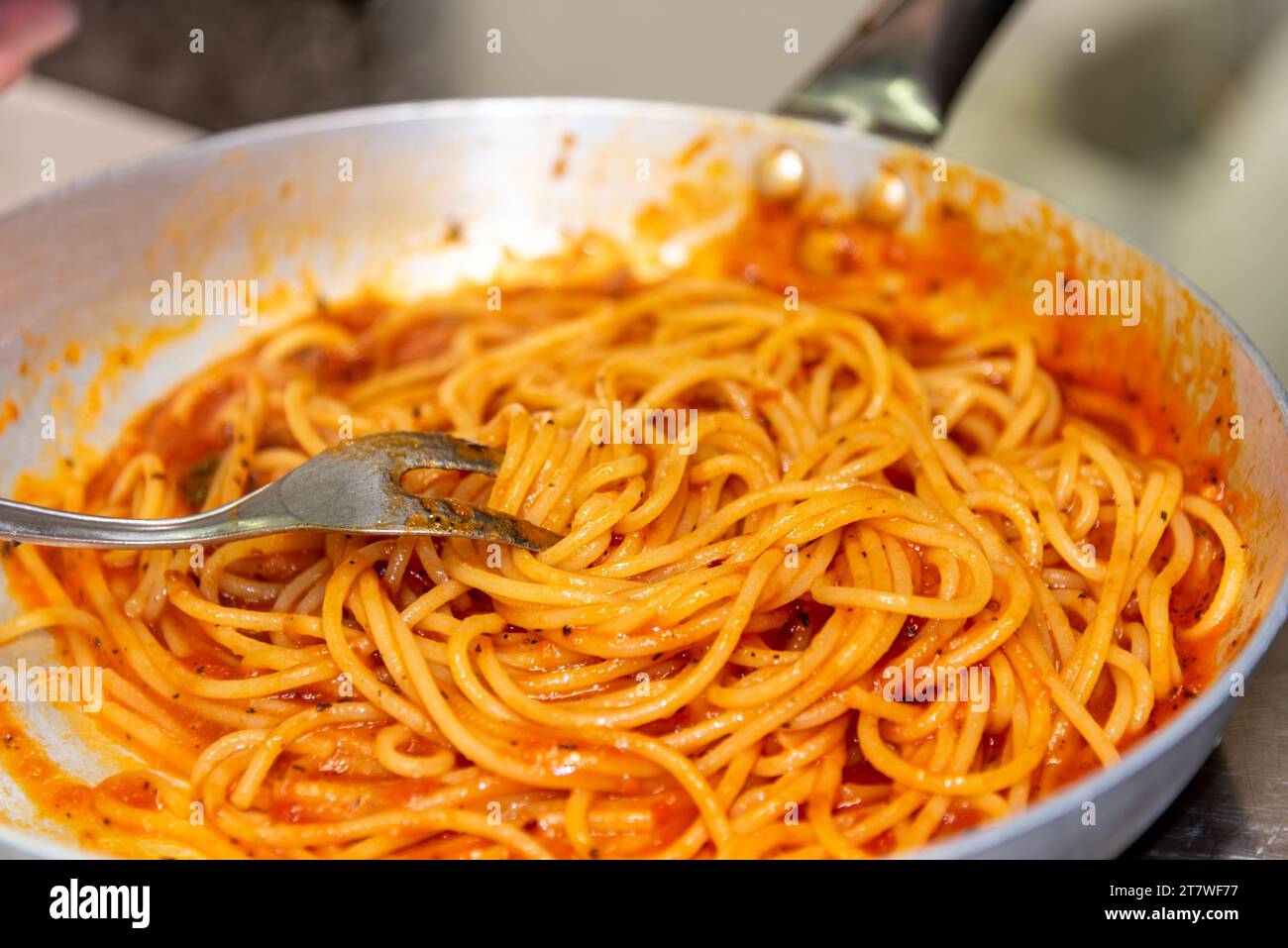 Spaghetti-Pasta mit Tomatensauce in der Pfanne mit Gabel, selektives Feuer aus der Nähe Stockfoto