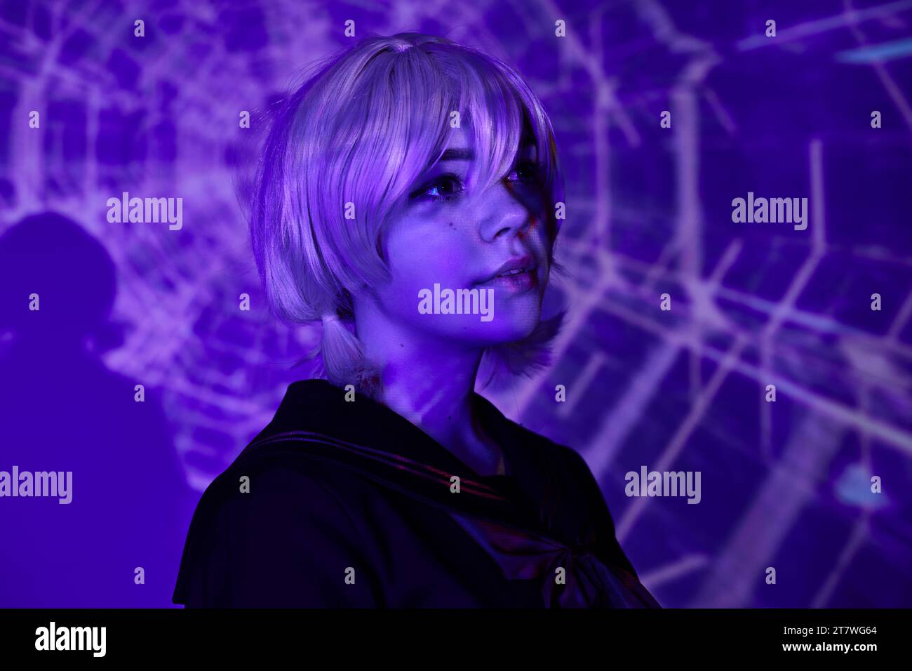 Porträt einer jungen Anime-Stil-Frau in blonder Perücke in blauem Neonlicht auf abstraktem Hintergrund, Cosplay Stockfoto