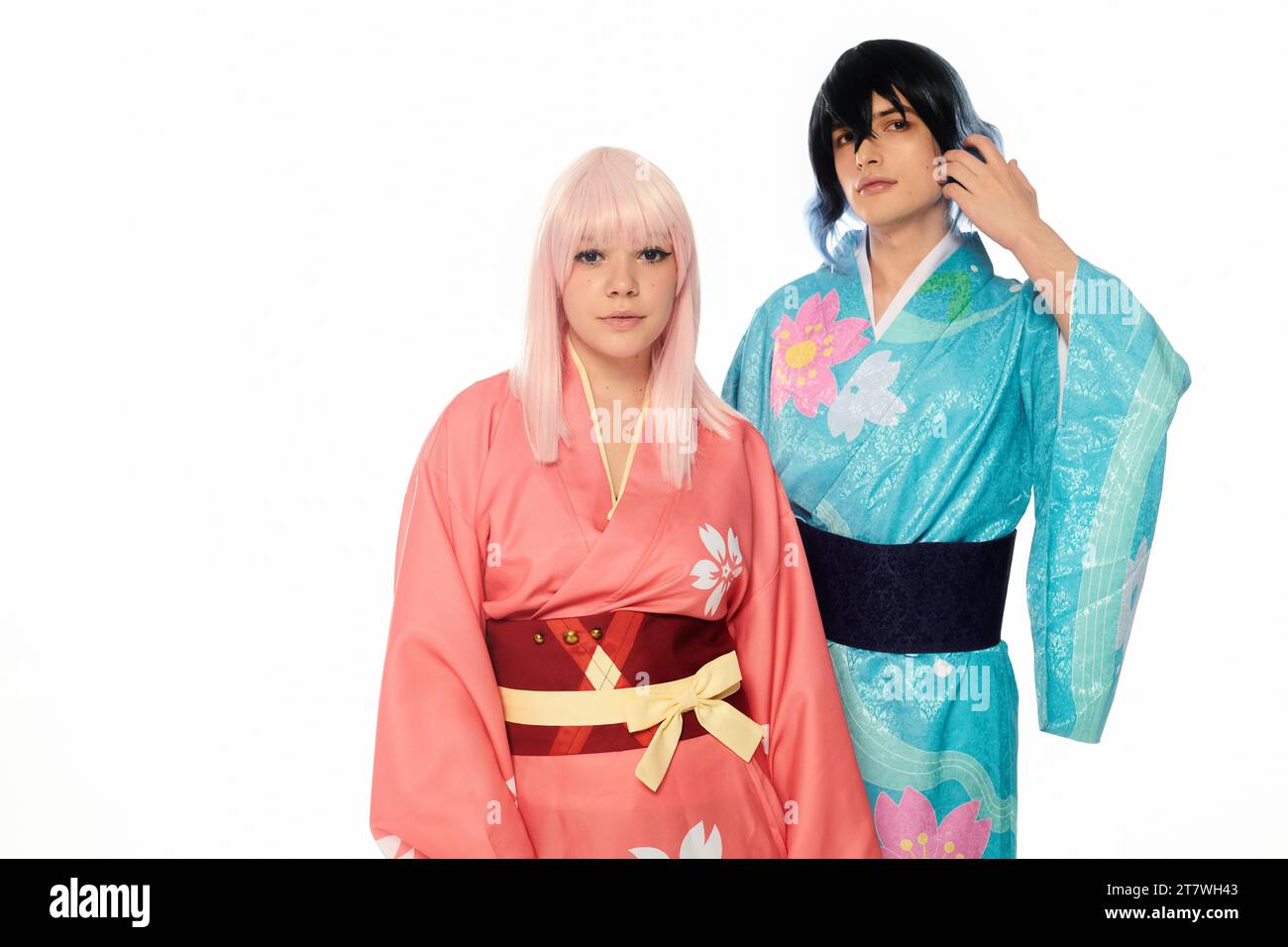 Junge Cosplay-Paar in bunten Kimonos und Perücken, die auf weißem, horizontalem Banner in die Kamera schauen Stockfoto