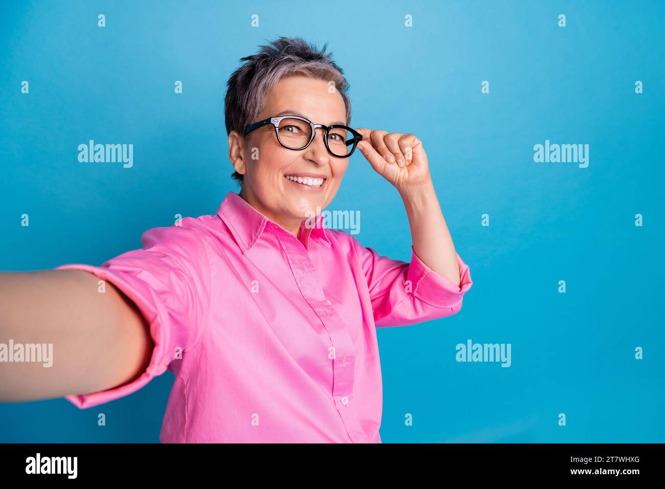 Foto einer optimistischen positiven Frau mit kurzer Frisur gekleideter rosa Bluse, die Selfie-Brille auf blauem Hintergrund macht Stockfoto